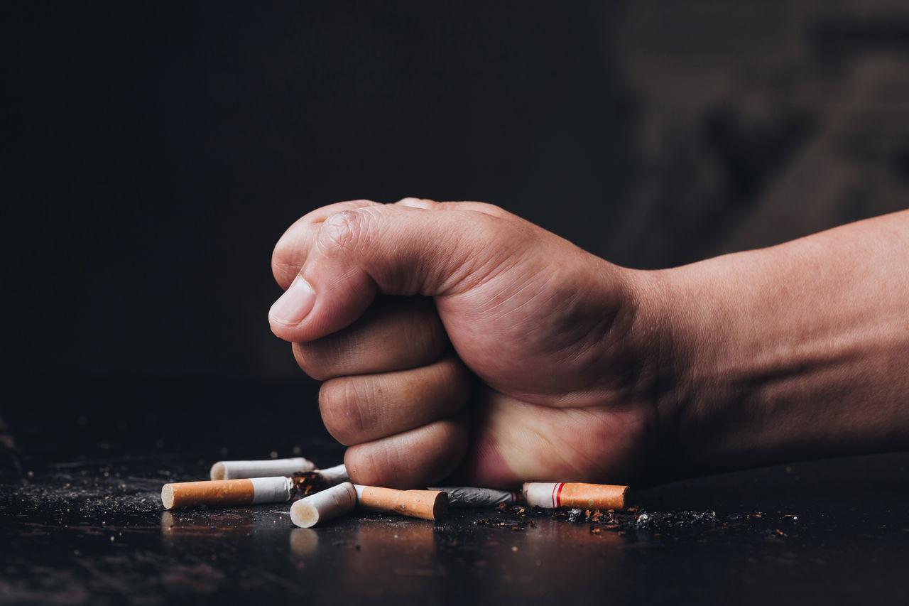Male hand destroying cigarettes on black background.stop smoking